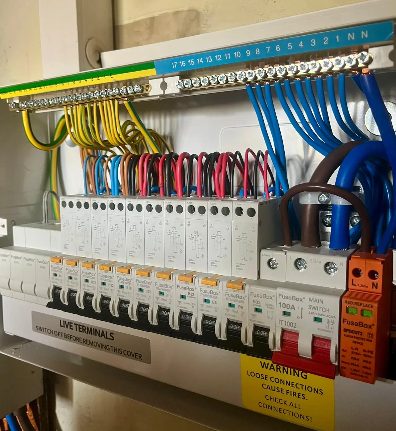 New consumer unit mid-install: labelled neutral and earth bars, colour-coded wiring dressed neatly and surge protection fitted