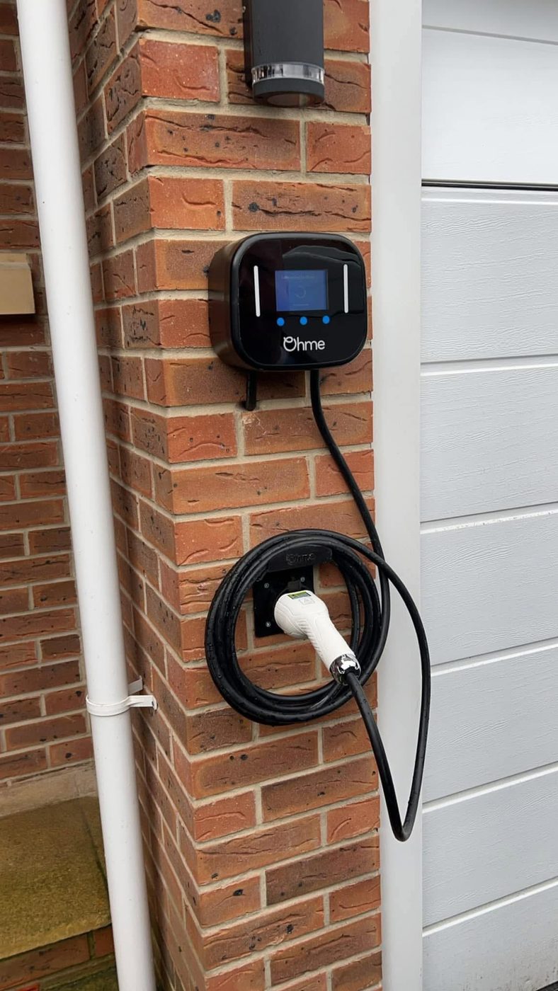 Ohme EV charge point mounted beside a garage door with a tidy external cable run