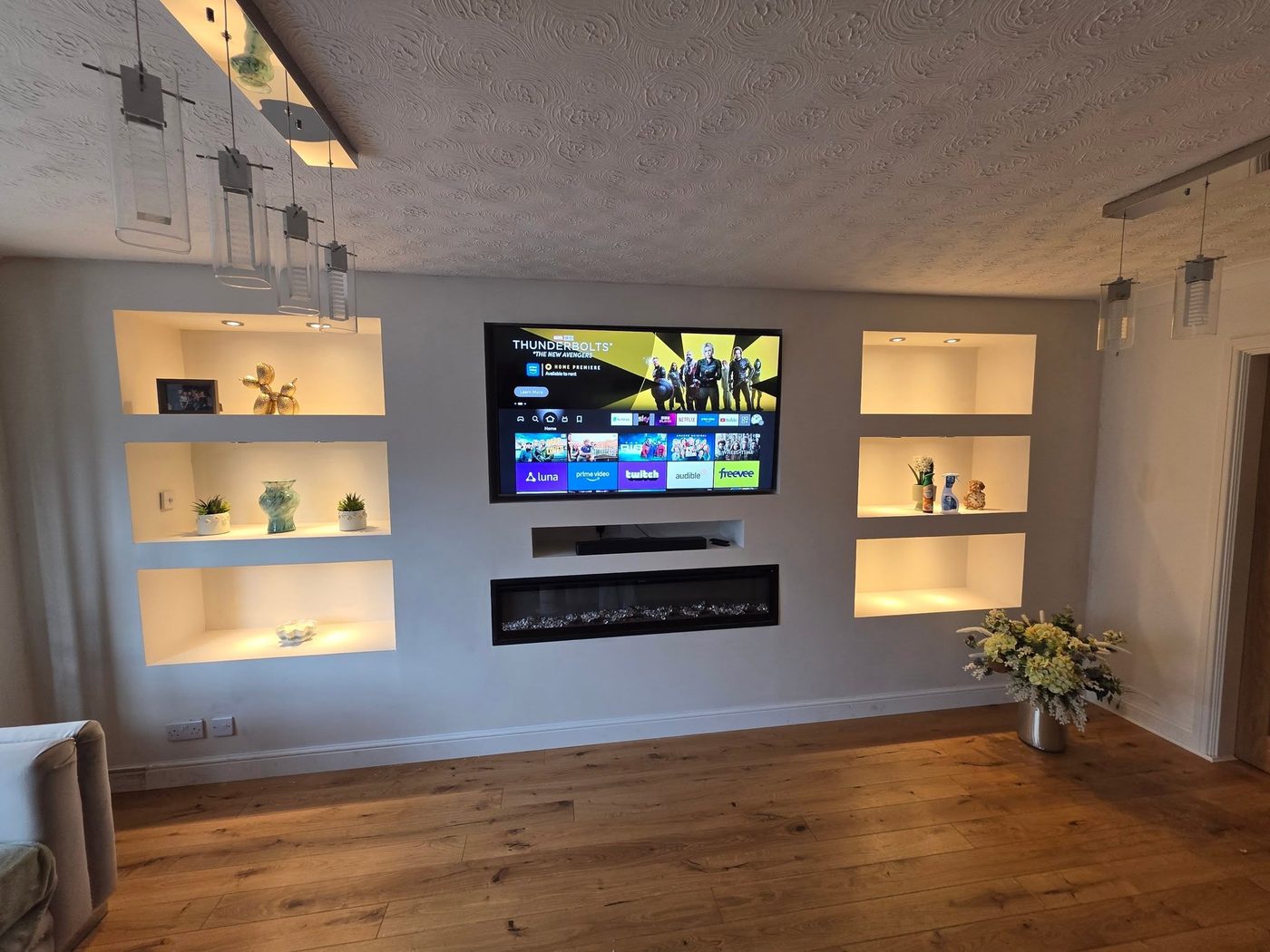 Finished white media wall with recessed TV, integrated electric fire and six backlit display niches